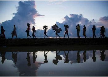Un grupo de migrantes y refugiados caminan en fila, cargando algunas pertenencias Foto: Acnur