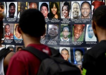 Em protesto após um ano da morte de Michael Brown, manifestantes estendem cartaz com foto de pessoas que foram mortas pela política