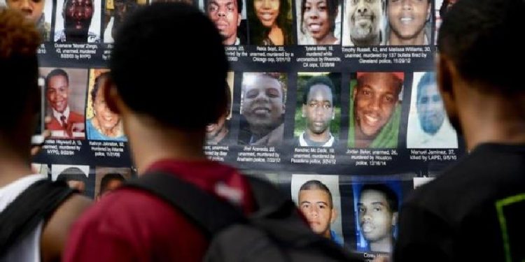 Em protesto após um ano da morte de Michael Brown, manifestantes estendem cartaz com foto de pessoas que foram mortas pela política Em protesto após um ano da morte de Michael Brown, manifestantes estendem cartaz com foto de pessoas que foram mortas pela política