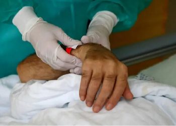 Una enfermera sostiene la mano de un enfermo de la covid-19 en un hospital en Berlín FABRIZIO BENSCH (REUTERS)